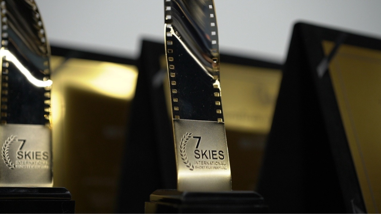 Golden film reel trophies of the 7 Skies International Short Film Festival displayed on stage